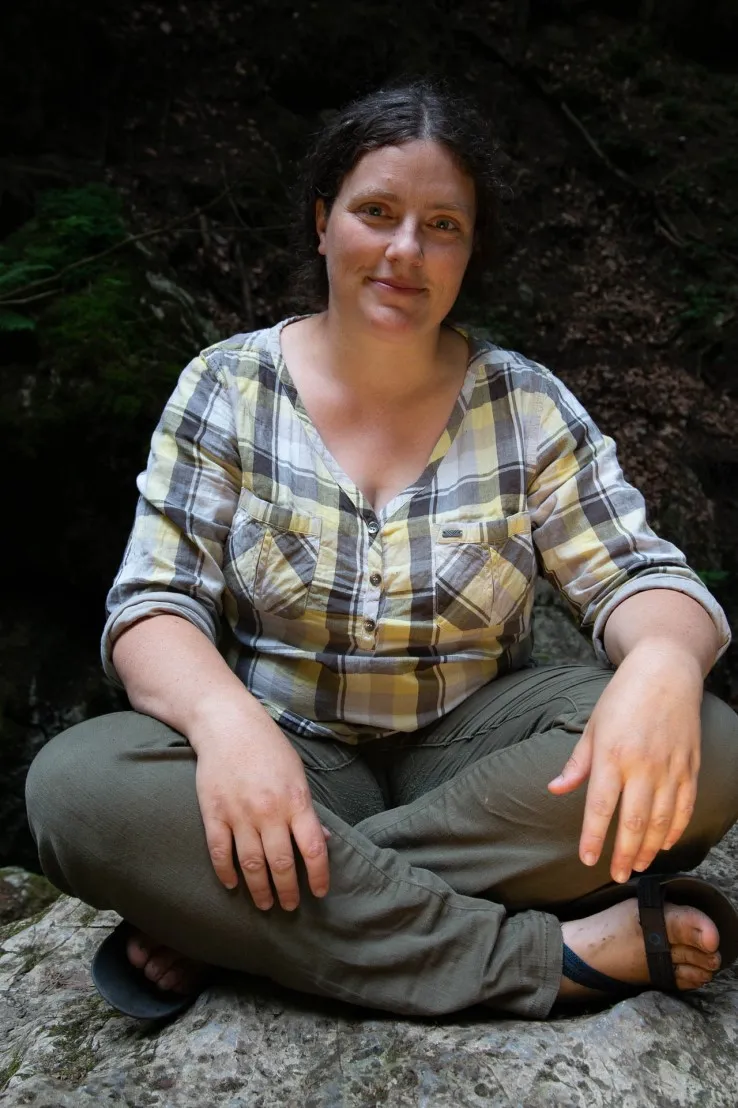 Anna Skryjová sedí se zkříženýma nohama na kameni